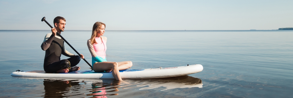 Man and woman wearing UV protective clothing on a paddleboard