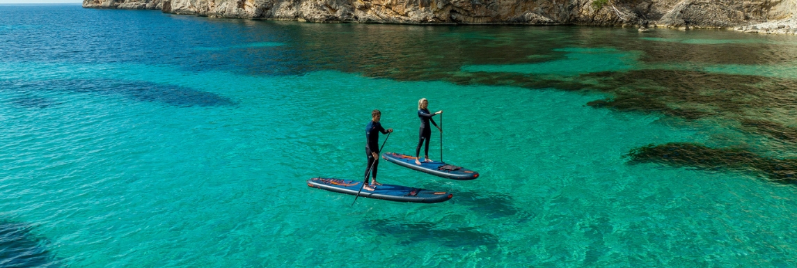 Hombre y mujer en traje de neopreno sobre una tabla de paddle surf