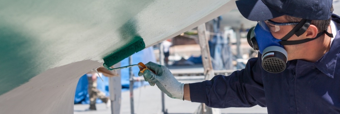 Hombre aplicando laca para barcos con un rodillo
