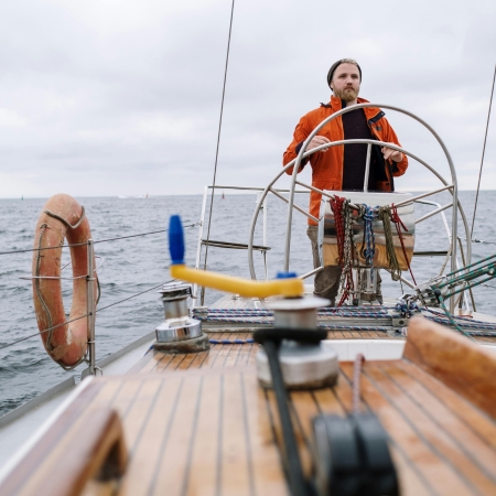 Navegador ao leme de seu barco com convés envernizado